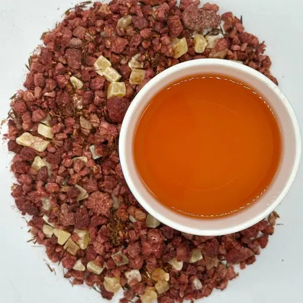 Raspberry Rooibos herbal tea brewed in a cup amid the loose-leaf blend — Dragon Girl Tea